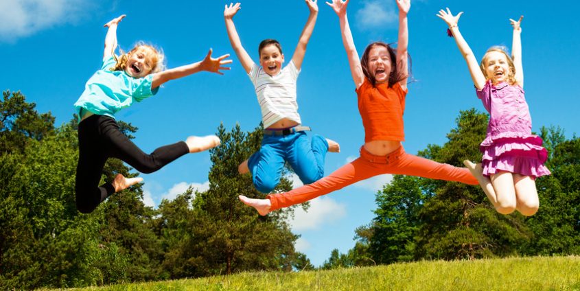 Vier Kinder springen im Gras