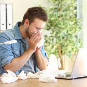 Krank zur Arbeit | Mann mit Taschentüchern vor dem Labtop