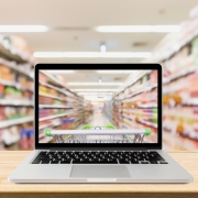 laptop computer on wood table with supermarket aisle blurred background online shopping concept