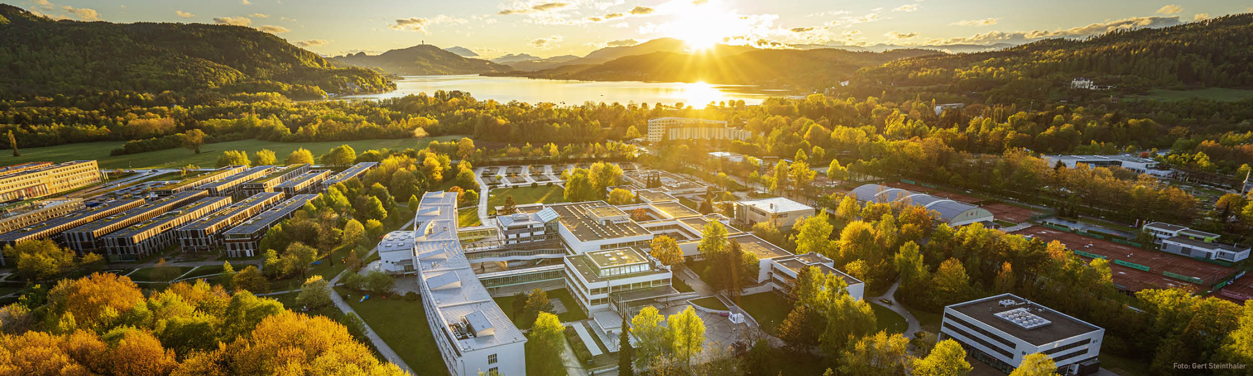Luftaufnahme der Universität Klagenfurt mit dem Wörthersee im Hintergrund (gegen die Sonne fotografiert)