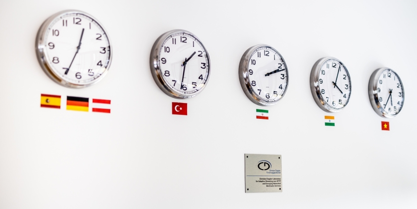 CD-Labor: Uhren zeigen die verschiedenen Zeitzonen der Herkunftsländer der Mitarbeiter*innen an
