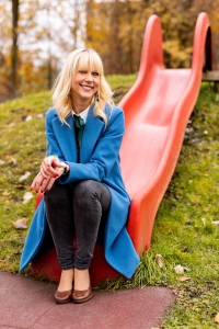 Veronika Michitsch sitzt auf einer roten Rutsche am Spielplatz des AAU Familienservice