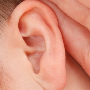 Hand hinter dem Ohr als Zeichen für Schwerhörigkeit