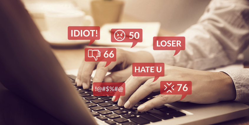 Menschen, die ein Notebook für die Interaktion mit sozialen Medien benutzen, mit Benachrichtigungssymbolen für Hassreden und gemeine Kommentare in sozialen Netzwerken