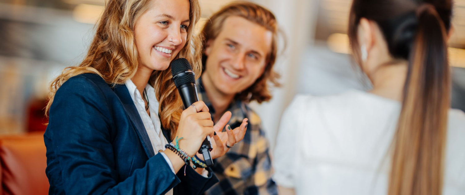 Studierende mit Mikrofon auf einem Sofa in der Aula