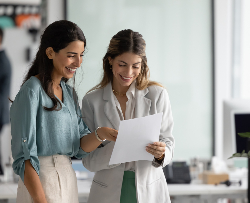 Gewinnen Sie mit unserem Karriere- und Netzwerkprogramm zukünftige Fachkräfte für sich oder nutzen Sie Kooperationsangebote und Forschungsinfrastruktur! | Foto: Adobestock/1667173470/fizkes Zwei Arbeitskolleg:innen stehen lächelnd nebeneinander und schauen auf ein Blatt Papier in der Hand der rechten Person.