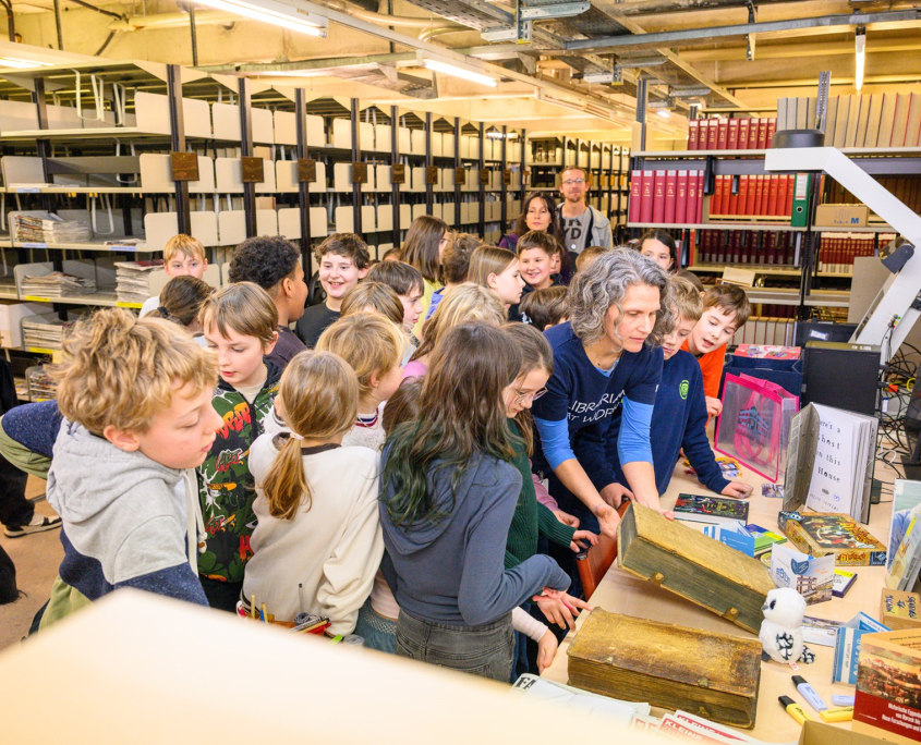 Ob in gemeinsamen Projekten, Diskussionen oder Veranstaltungen – Ihre Perspektiven bereichern unsere Forschung und Lehre. Lassen Sie uns gemeinsam Fragen stellen, Antworten finden und Zukunft gestalten! | Foto: Thomas Hude Zahlreiche Kinder stehen in der Bibliothek und schauen sich interessiert alte Bücher an.