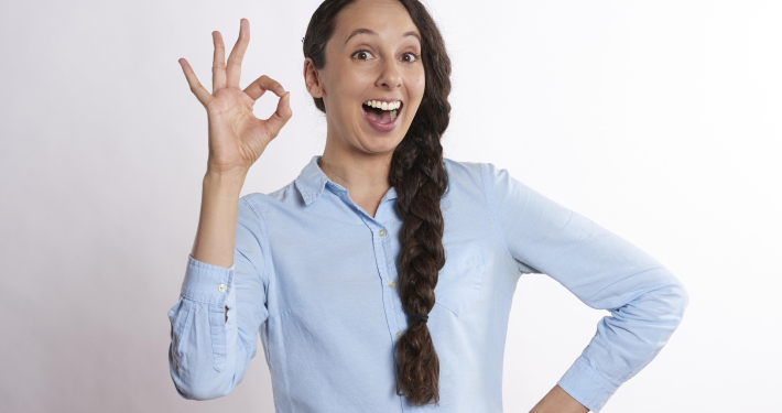 junge Frau, lächelt und zeigt die Gebärde super